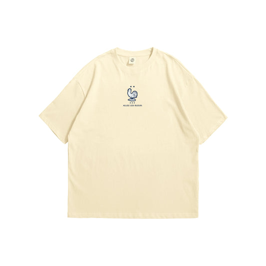 A cream oversized t-shirt shown from the front and back, featuring a small blue France FFF rooster on the chest and a large intricate navy line-art illustration of a rooster containing French landmarks on the reverse - sports streetwear apparel by Stick-On Limited.
